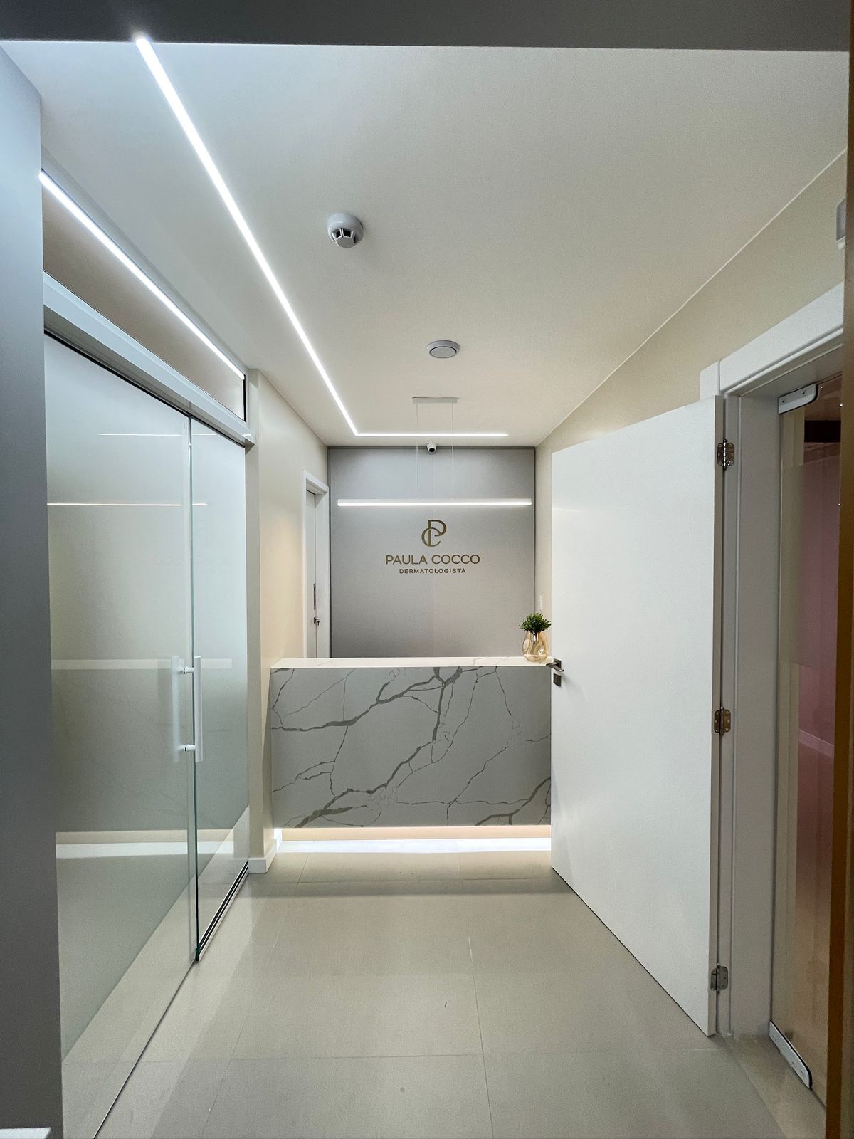 Recepção de clínica dermatologista com bancada em mármore — Jéssica Nicola Arquitetura